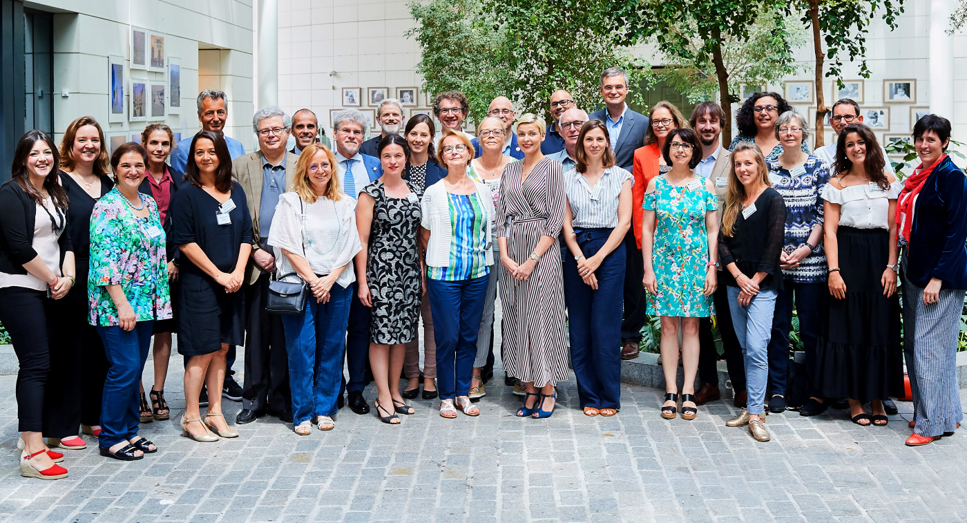 A diverse group of people stands united in front of a building, showcasing community spirit.